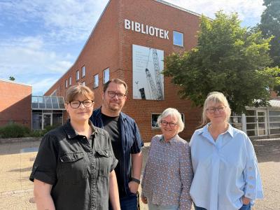 fire bibliotekarer står ude foran biblioteket