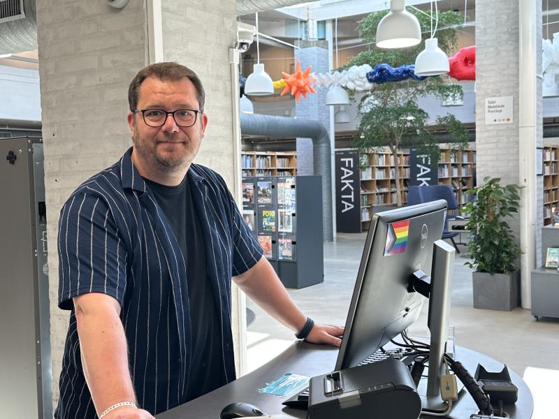 Bibliotekar står ved skranken og byder velkommen