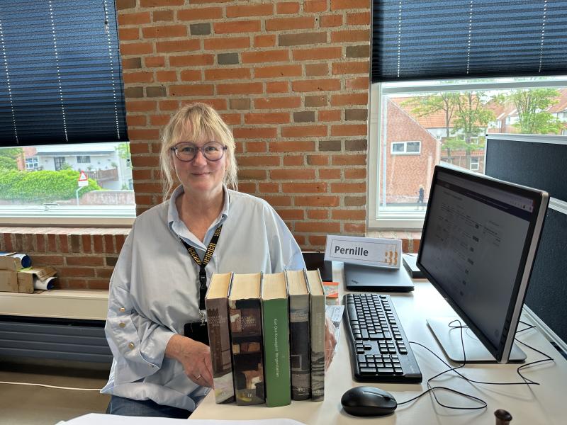 Bibliotekar sidder på sit kontor med en bunke bøger
