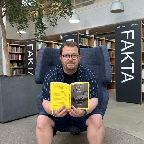 Bibliotekar sidder med bog i biblioteket