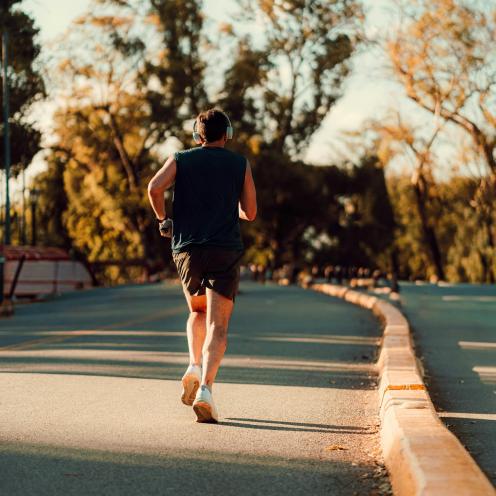 Løber set bagfra på en bred vej i aftensol.