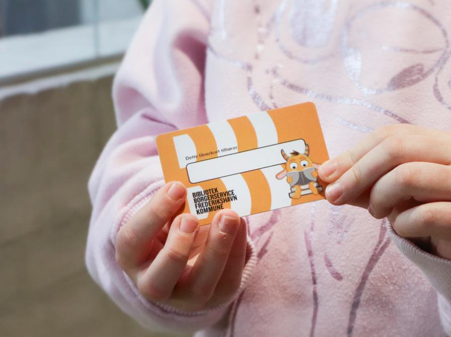 Billede af børnehænder med lånerkort i hånden