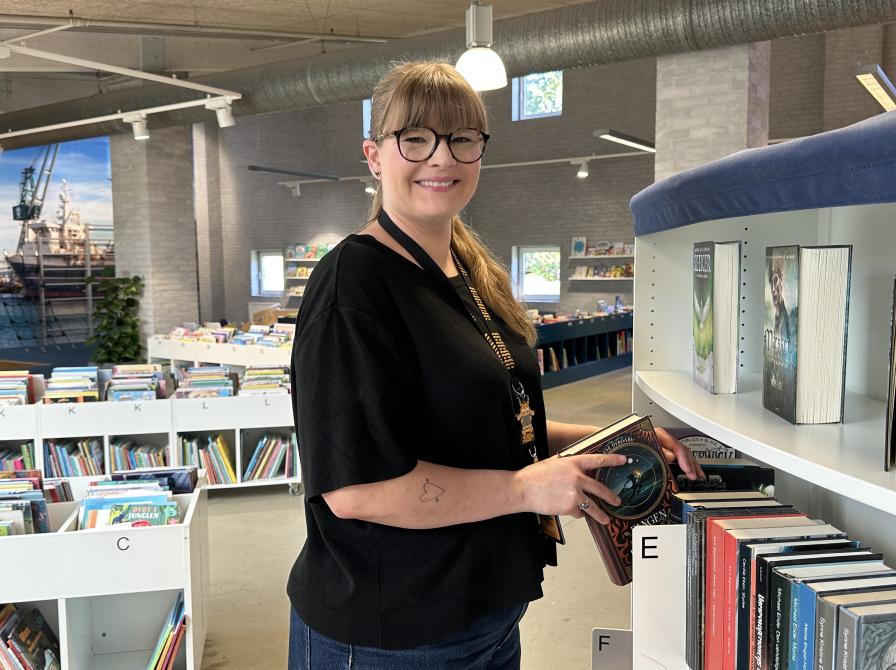 Bibliotekar står på biblioteket og sætter bøger på plads