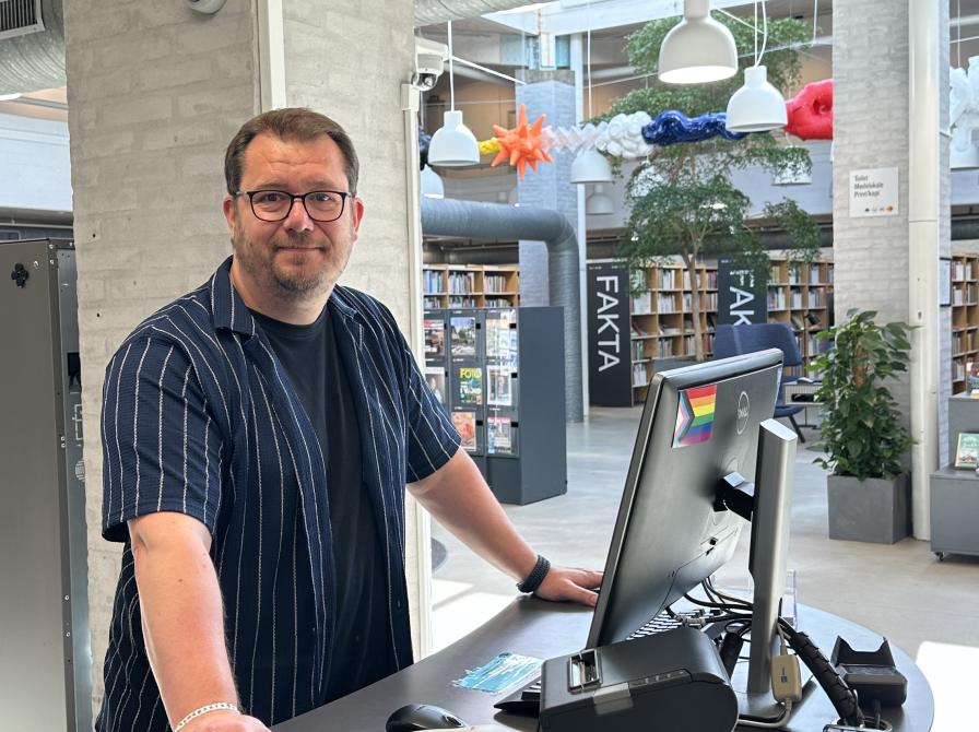 Bibliotekar står ved skranken og byder velkommen