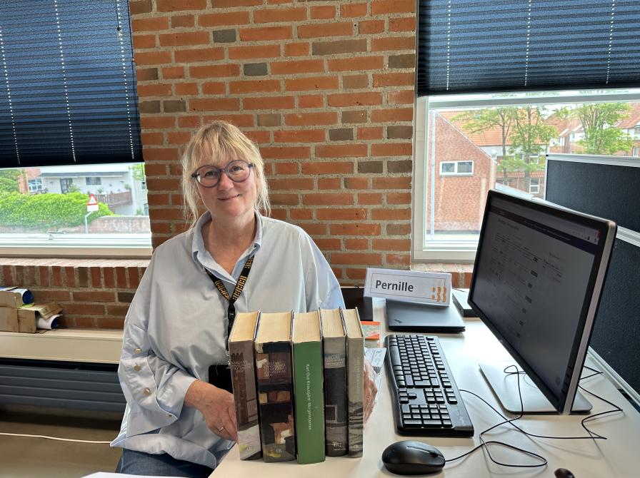Bibliotekar sidder med bogbunke på sit kontor