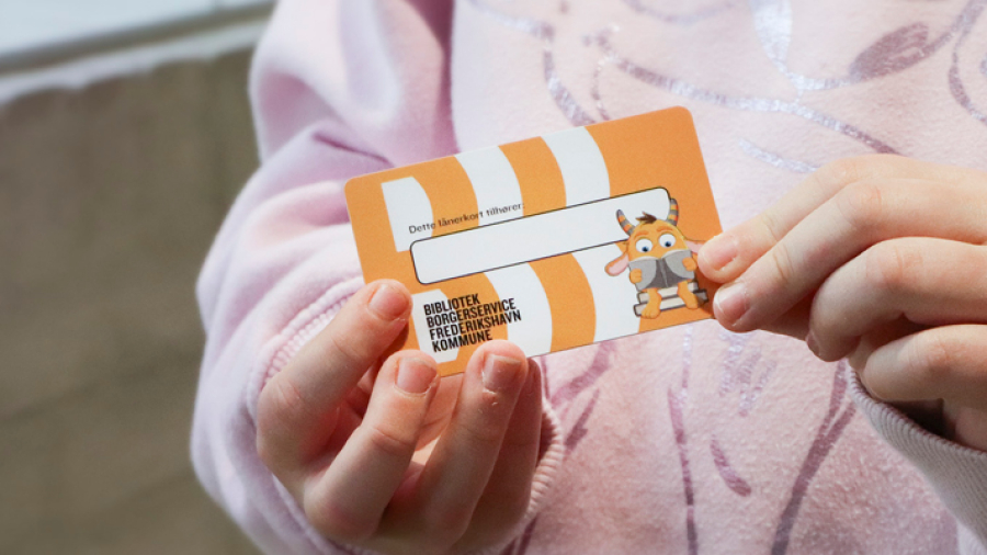 Billede af børnehænder der holder et lånerkort for børn